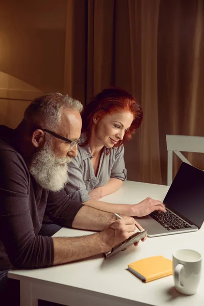 Pareja de mediana edad trabajando en el ordenador portátil - foto de stock