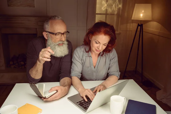 Pareja de mediana edad trabajando en el ordenador portátil - foto de stock