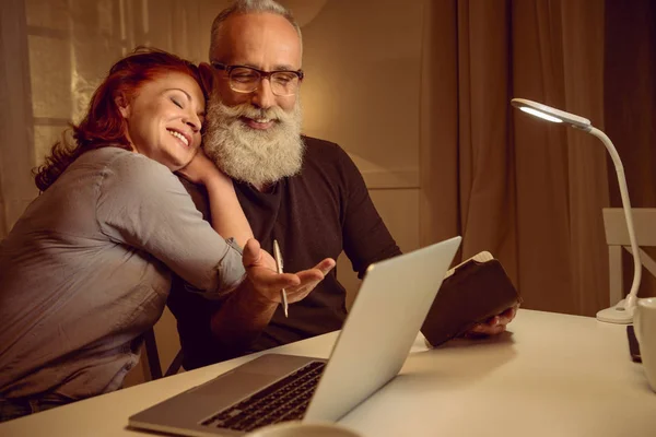 Пара средних лет сидит рядом с ноутбуком — стоковое фото
