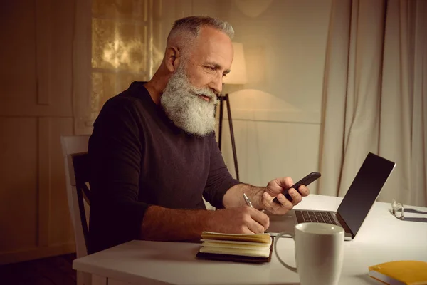 Grauhaariger Mann arbeitet zu Hause — Stockfoto