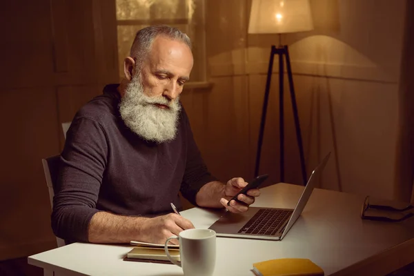 Homme aux cheveux gris travaillant à la maison — Photo de stock