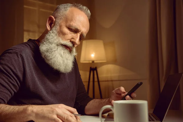 Homme aux cheveux gris travaillant à la maison — Photo de stock