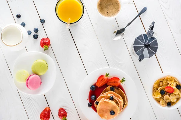 Pfannkuchen mit Macarons und Kaffee auf Holztischplatte — Stockfoto