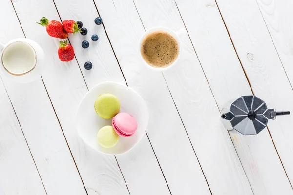 Macarons com café e morangos em mesa de madeira — Fotografia de Stock