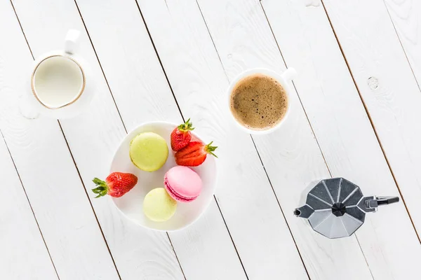 Macarons with coffee and strawberries on wooden tabletop — Stock Photo