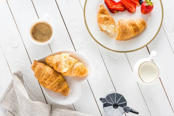 Croissants mit Kaffee und Erdbeeren auf Holztischplatte — Stockfoto