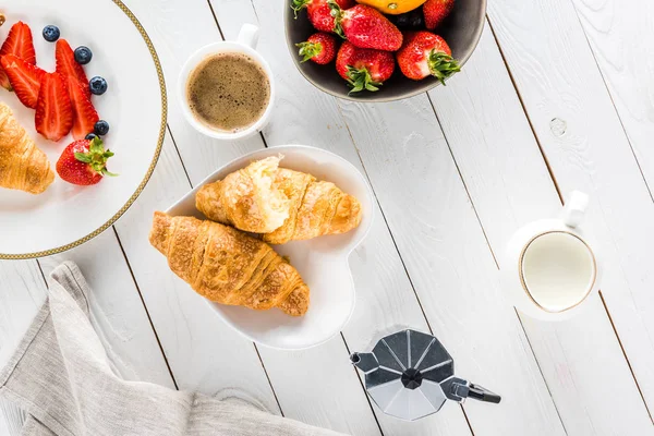 Croissants mit Kaffee und Erdbeeren auf Holztischplatte — Stockfoto