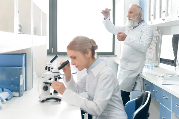 Учёные в белых халатах в лаборатории — стоковое фото