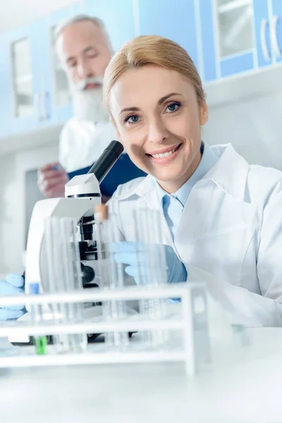 Químico trabajando con microscopio - foto de stock
