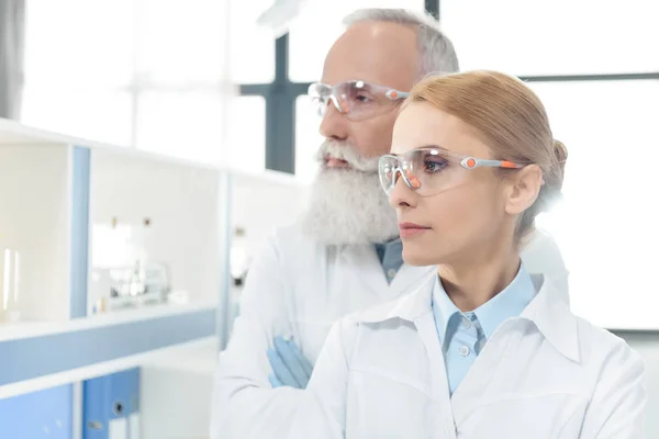 Учёные в белых халатах в лаборатории — стоковое фото