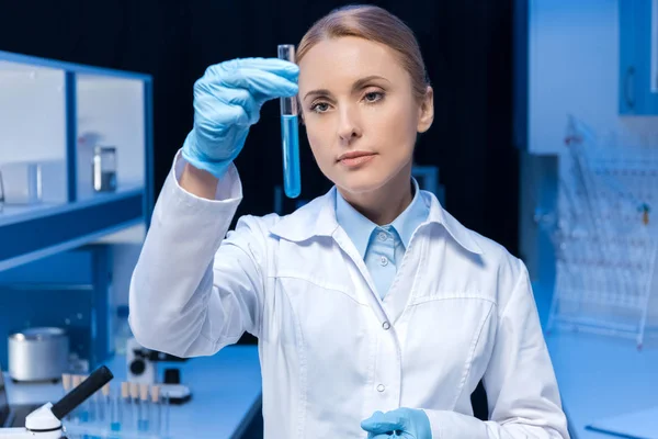 Técnico de laboratorio mirando tubo con reactivo - foto de stock