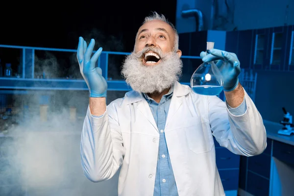 Mature scientist holding flask — Stock Photo