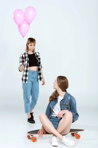 Mujeres jóvenes con monopatín y globos - foto de stock