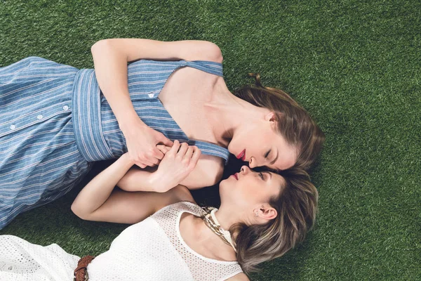Lesbian couple kissing while lying on grass — Stock Photo
