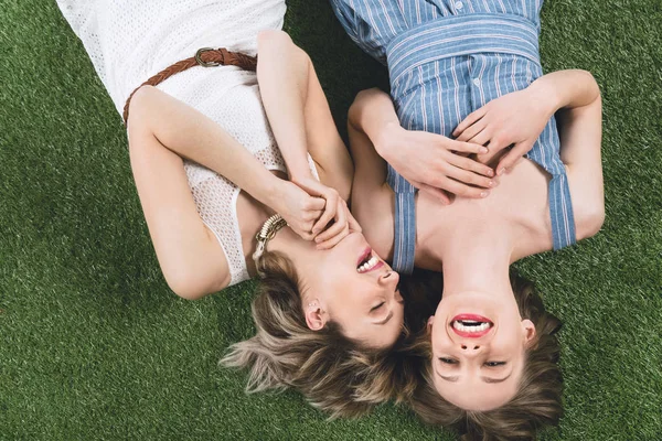 Lesbian couple laughing while lying on grass — Stock Photo