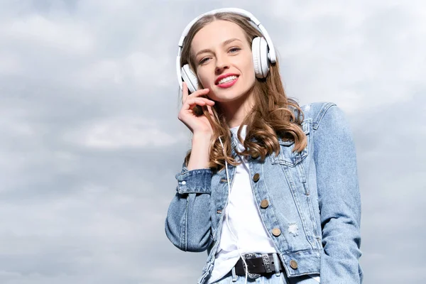 Jovem mulher ouvindo música em fones de ouvido — Fotografia de Stock