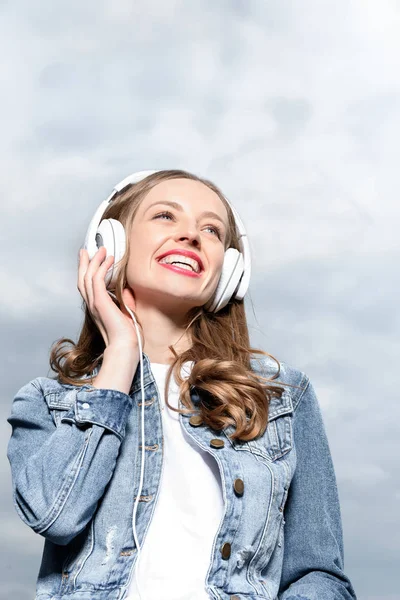 Chica sonriente escuchando música en auriculares - foto de stock
