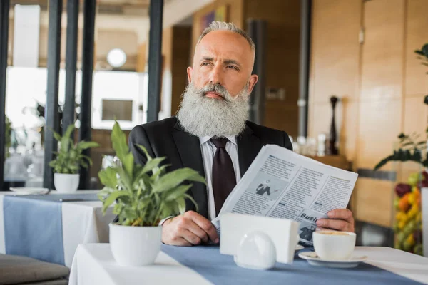 Thoughtful businessman with newspaper — Stock Photo