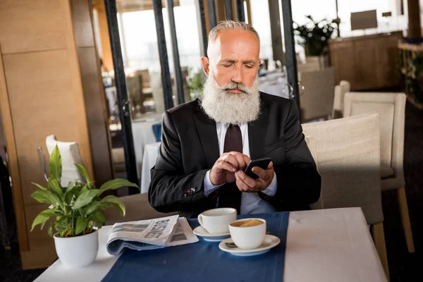 Uomo d'affari che utilizza lo smartphone nel ristorante — Foto stock