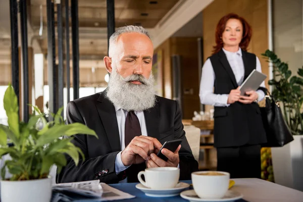 Businessman using smartphone in restaurant — Stock Photo