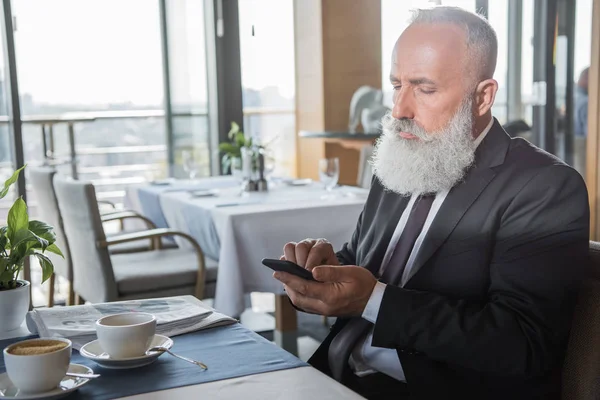 Homme d'affaires utilisant smartphone dans le restaurant — Photo de stock