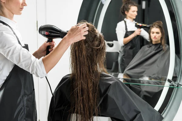 Парикмахер сушит волосы женщины — стоковое фото