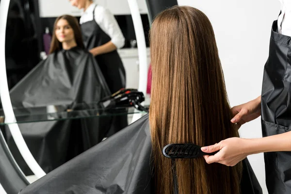 Parrucchiere spazzolando capelli di donna — Foto stock