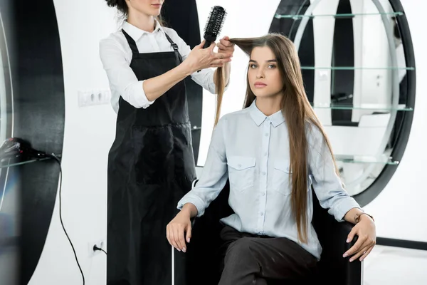 Hairdresser brushing hair of woman — Stock Photo