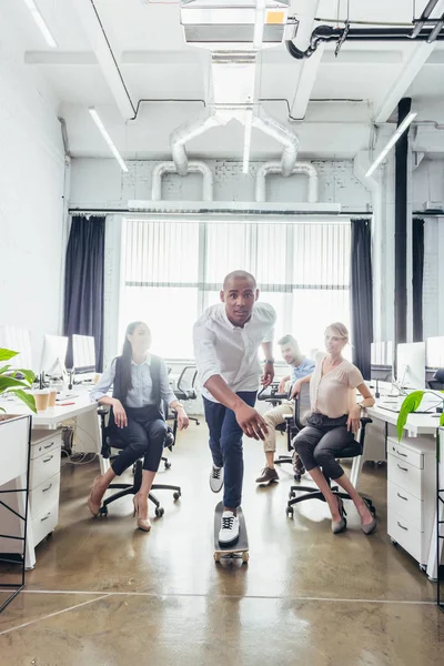 Businessman on skateboard in office — Stock Photo