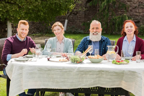 Famiglia sorridente durante la cena in campagna — Foto stock