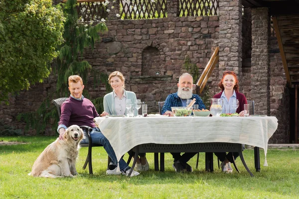 Familia sonriente durante la cena en el campo - foto de stock