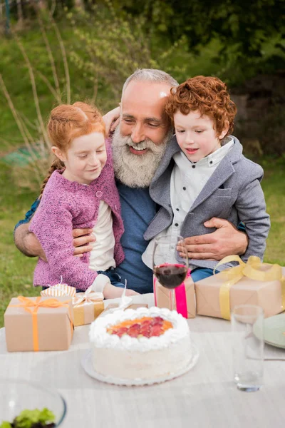 Дети поздравляют дедушку на праздновании дня рождения — стоковое фото