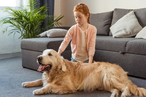 Child petting dog at home — Stock Photo