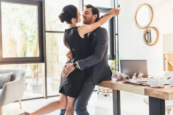 Young couple embracing in office — Stock Photo