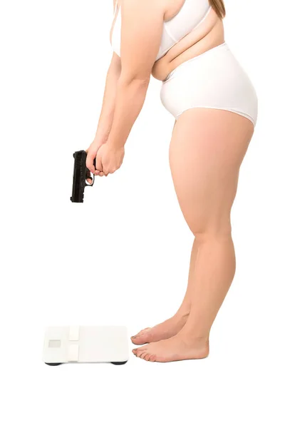 Толстая женщина с пистолетом стоит на весах — стоковое фото