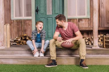 father with son sitting on porch 