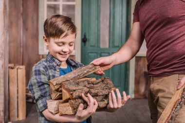 father with son collecting wood logs clipart