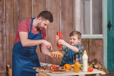 Father and son cooking hot dog  clipart