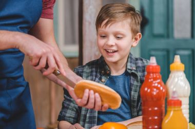 Father and son cooking hot dog  clipart