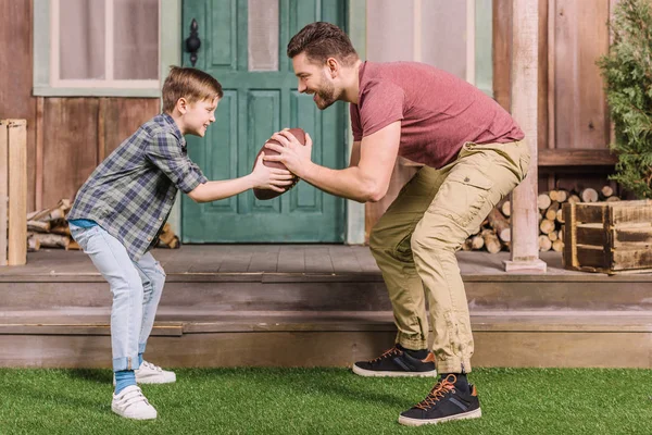 Батько з сином грає з м'ячем на задньому дворі — стокове фото