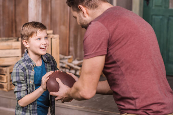 father with son playing with ball at backyard