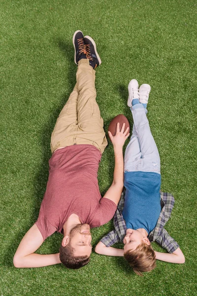 Батько з сином лежить на траві — стокове фото