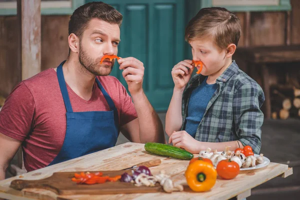 Pai e filho cortando legumes — Fotografia de Stock