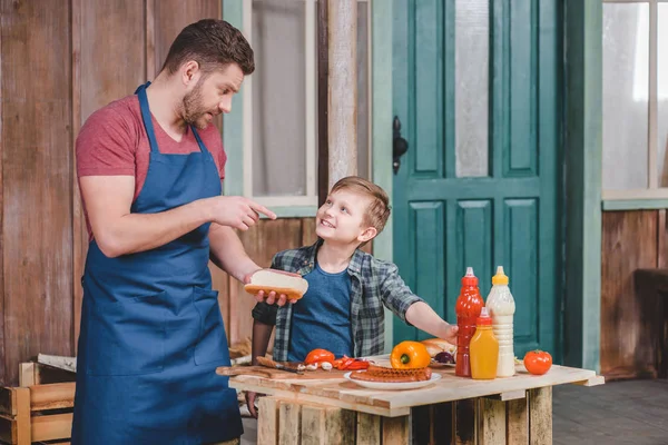 Father and son cooking hot dog — Stock Photo, Image