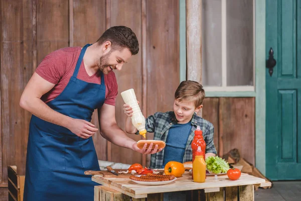Far och son matlagning varmkorv — Stockfoto