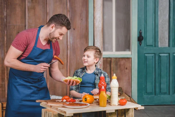 Padre e hijo cocinando hot dog — Foto de Stock