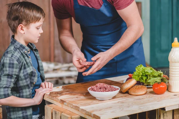 Pai e filho cozinhando hambúrgueres — Fotografia de Stock