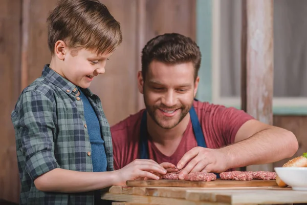 Padre e hijo cocinando hamburguesas — Foto de Stock