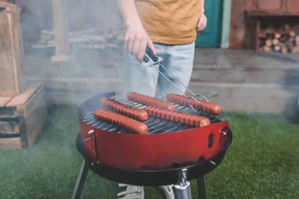 Menino cozinhar salsichas de cachorro quente — Fotografia de Stock