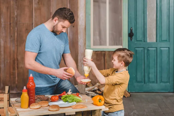 Dad and son cooking burgers — Free Stock Photo